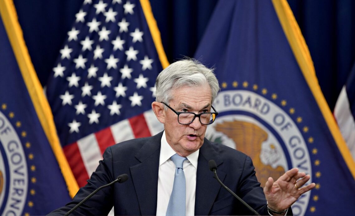 Fed Chair Jerome Powell stands in front of reporters at a news conference