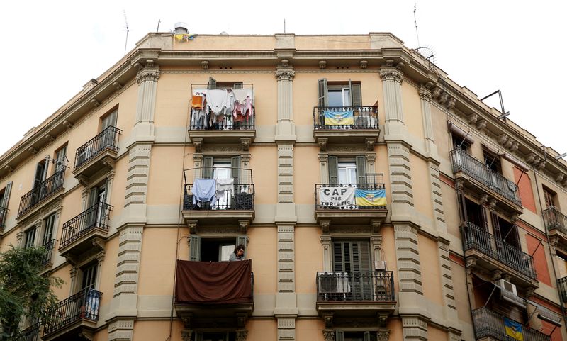 © Reuters. FILE PHOTO: A banner against apartments for tourists hangs from a balcony as a woman tend clothes at Barceloneta neighborhood in Barcelona, Spain, November 28, 2016. The banner reads