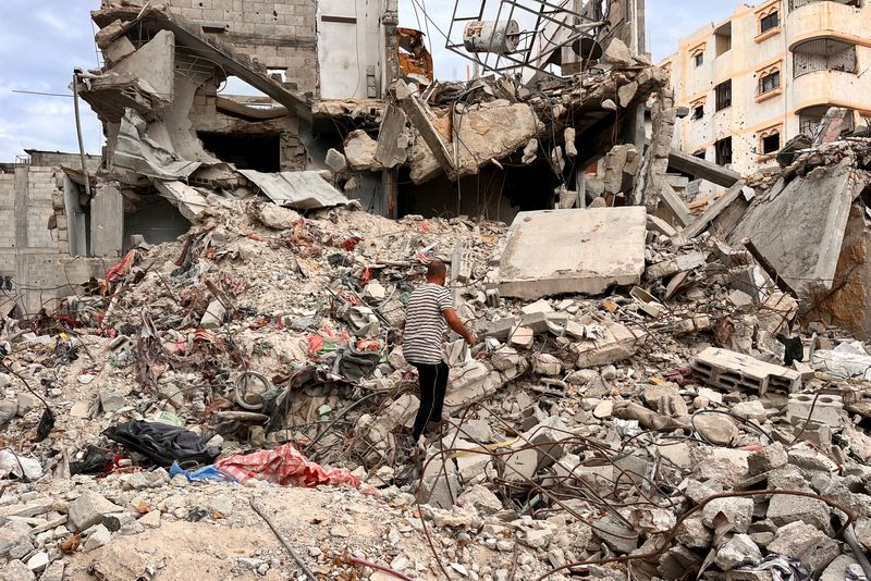 © Reuters. Palestinian man Moein Abu Odeh searches for clothes through the rubble of a house destroyed in the Israeli military offensive, in Khan Younis in the southern Gaza Strip, November 18, 2024. REUTERS/Hussam Al-Masri     TPX IMAGES OF THE DAY