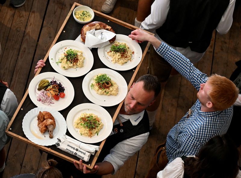 © Reuters. FILE PHOTO: A waiter carries food on the day of the official opening of the 189th Oktoberfest, the world's largest beer festival in Munich, Germany, September 21, 2024. REUTERS/Angelika Warmuth/File Photo