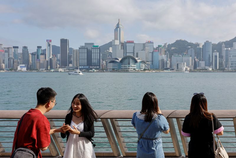 © Reuters. FILE PHOTO: Mainland Chinese tourists take photo of the skyline of buildings at Tsim Sha Tsui, in Hong Kong, China May 2, 2023. REUTERS/Tyrone Siu/File photo