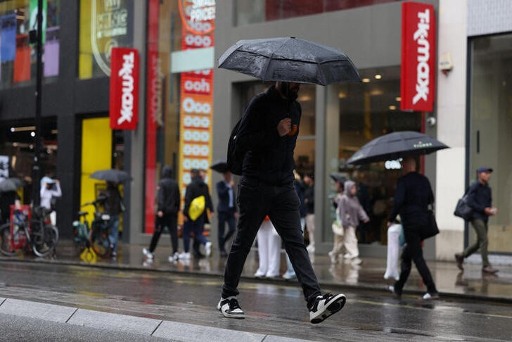 © Reuters. FILE  PHOTO: Shopper holds an umbrella while crossing the road on Oxford Street in London, Britain, July 9, 2024. REUTERS/Hollie Adams/File Photo